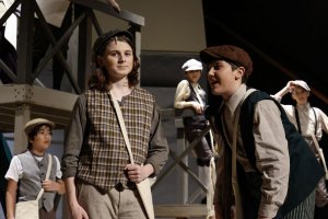 Middle school actors on stage in a performance of Newsies, Jr.